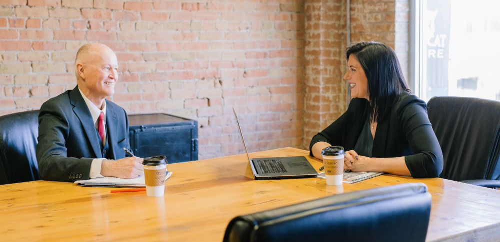 An instructional designer interviewing a tenured senior coworker in the board room.