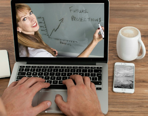 The same female teacher conducting an online class as seen from the laptop of a learner.
